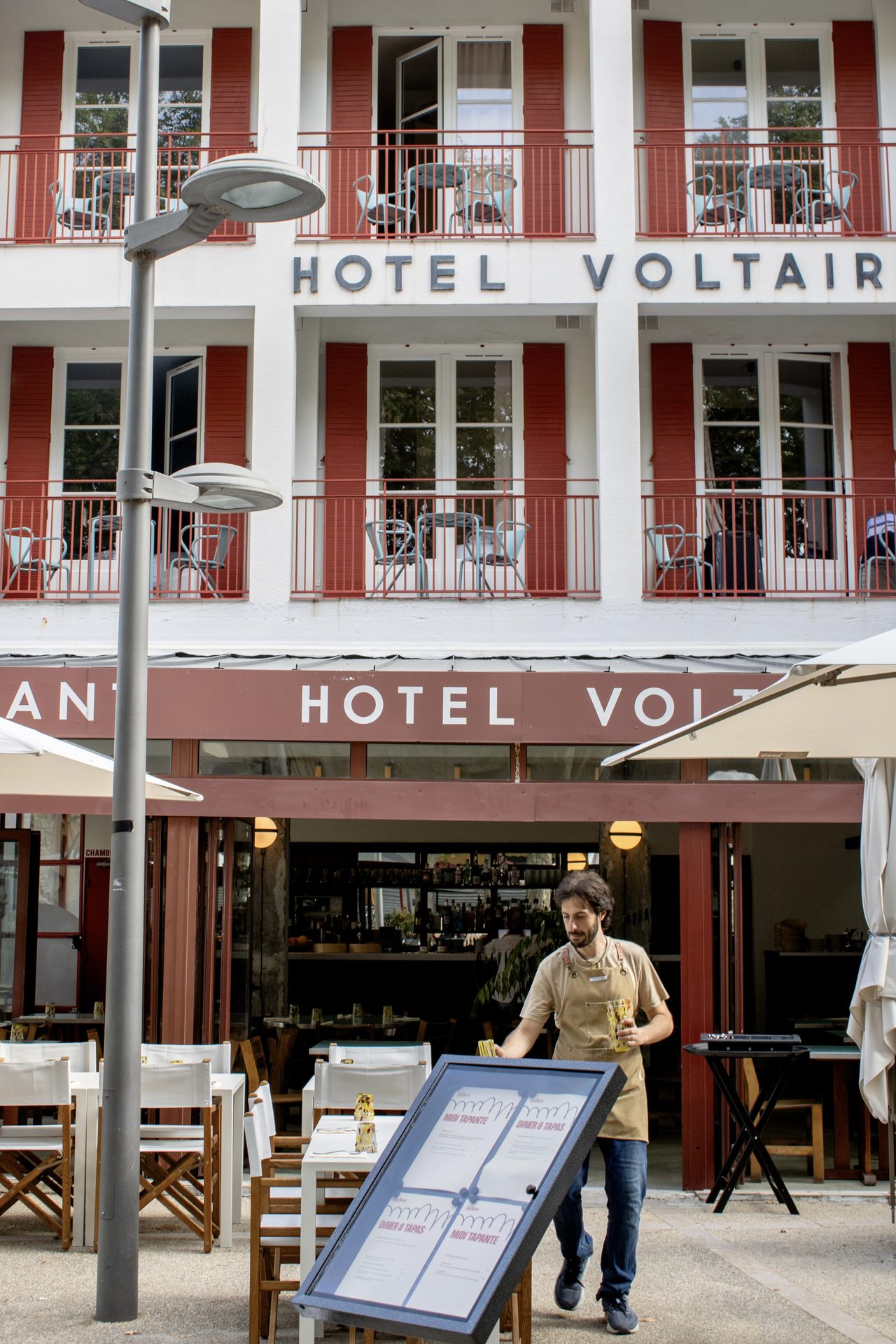 Façade de l'Hôtel Voltaire à Arles, terrasse et parasols blancs